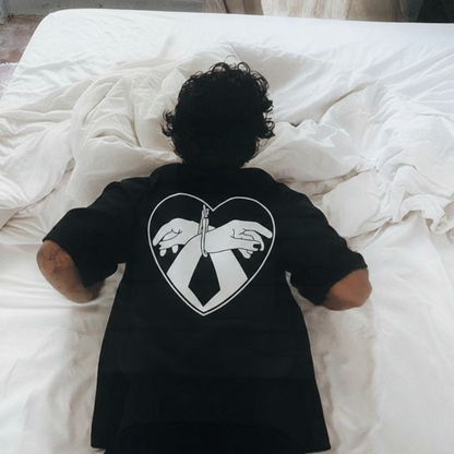 A bacl tshirt with a bdsm print on the back showing two hands tied in a black love heart